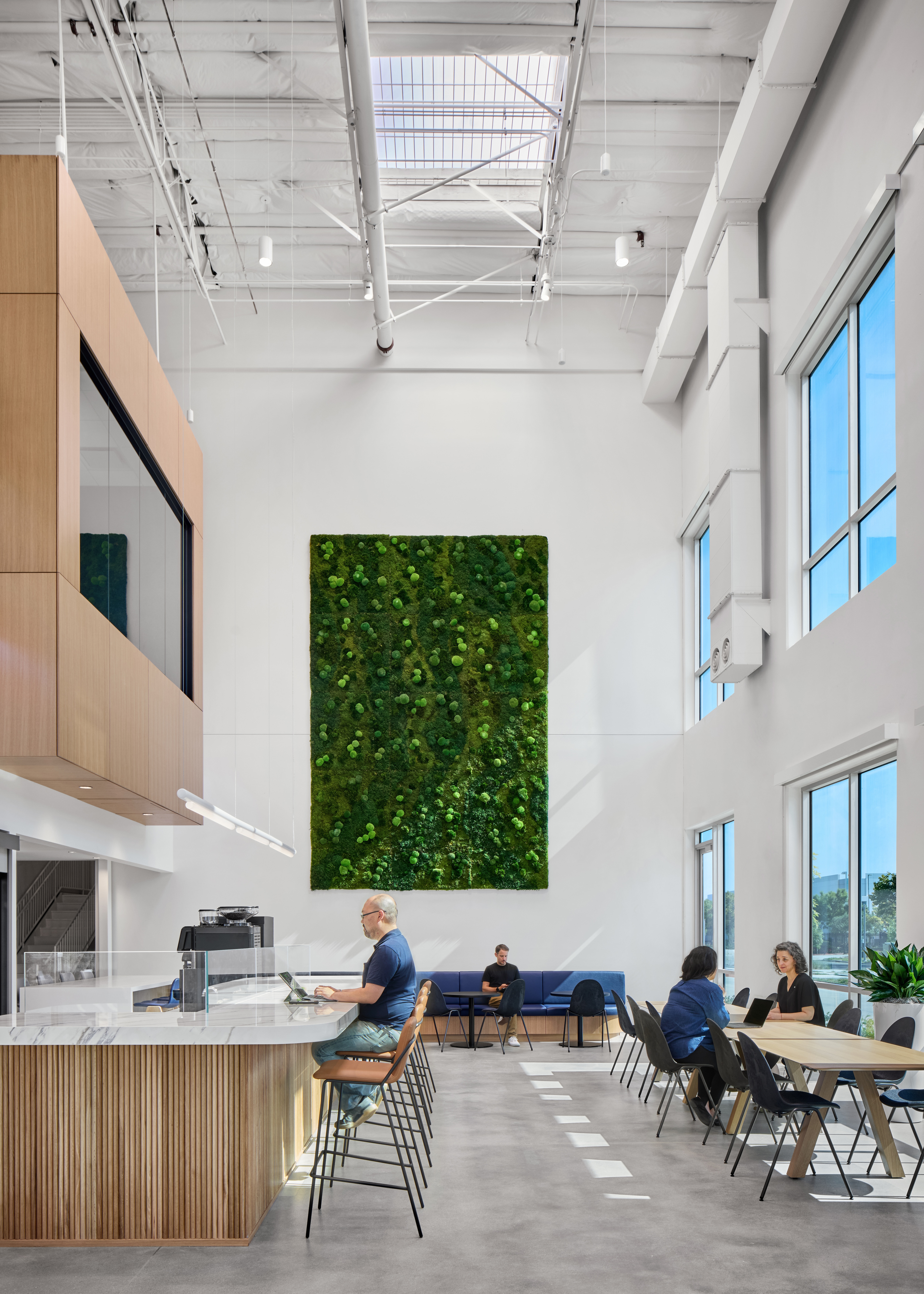 An architectural rendering of an office space with natural wood tones, white walls, open space, plant accents and a lot of natural light. 